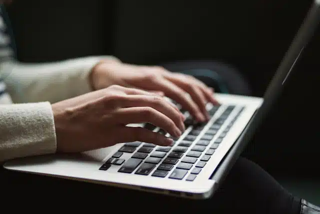 Close-up of hands typing on a laptop, applying for an online loan