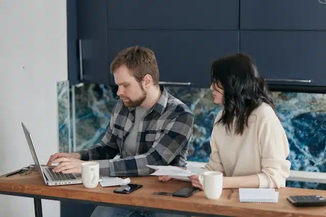 A couple analyzing their financial health at home with a laptop and documents.