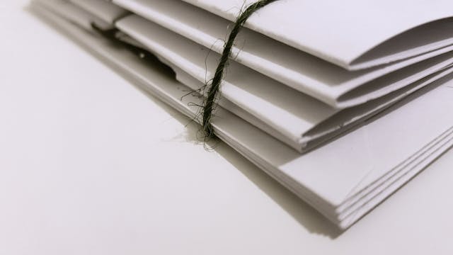 A neat stack of documents tied with a black ribbon, symbolizing the paperwork required for a title pawn application. 